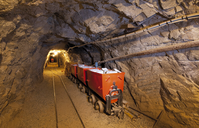 Carrelli rossi carichi di talco sui binari della galleria mineraria.