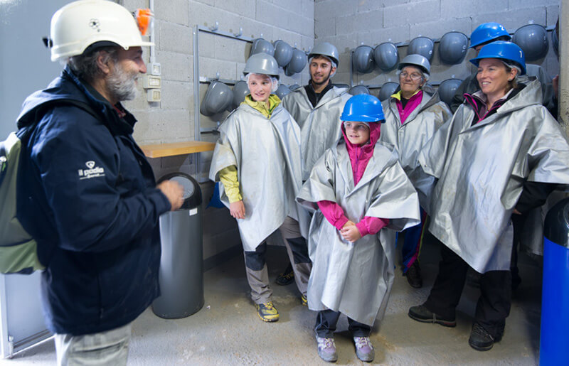 Guida accoglie i visitatori con caschi e mantelline prima di ScopriAlpi.