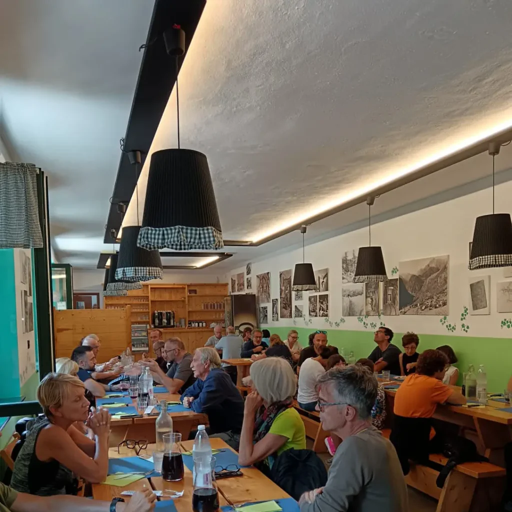 Persone sedute a tavoli in legno nella sala interna del Bistrot del Minatore